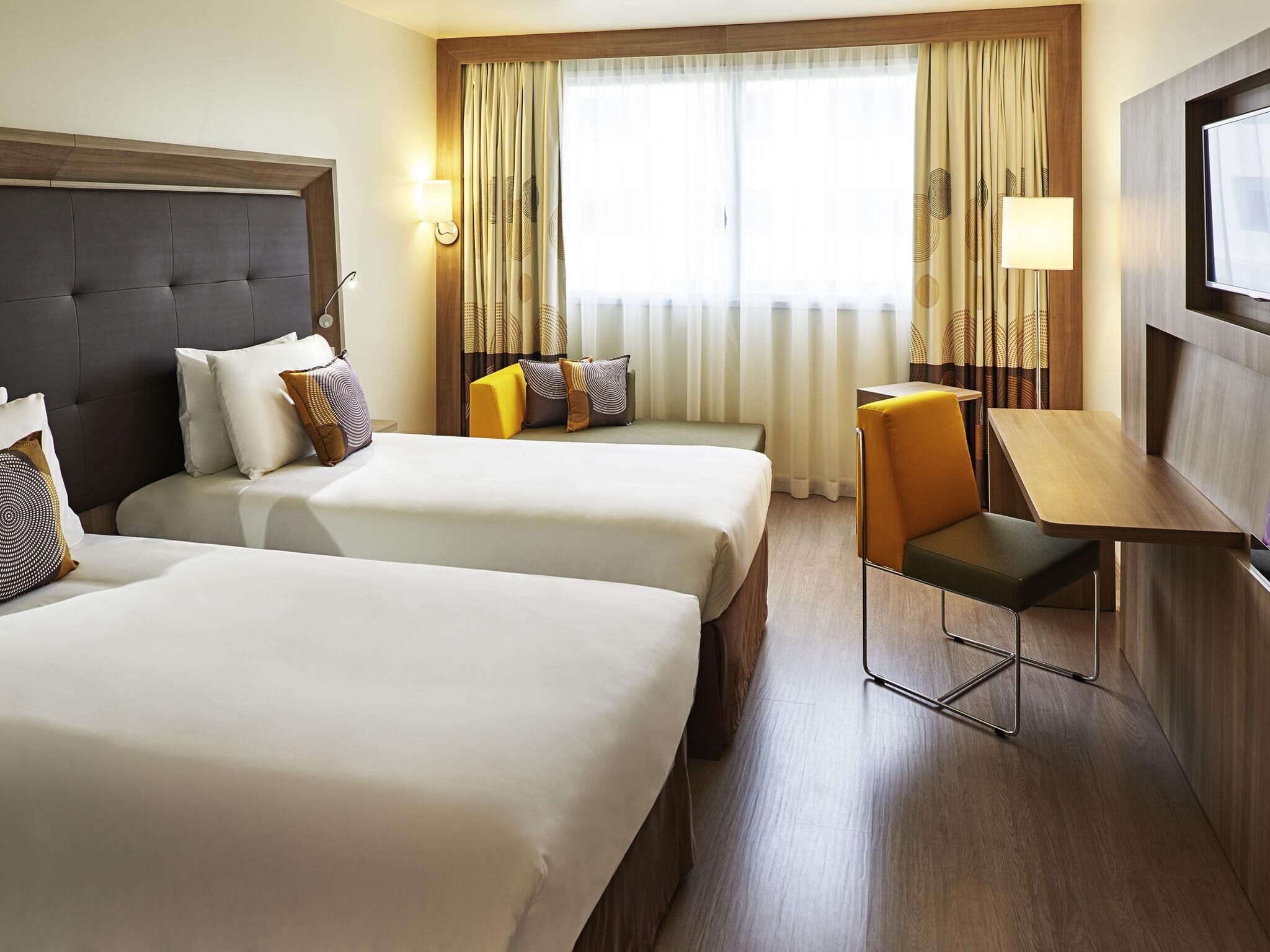 A hotel room with two beds, a desk, and a chair.