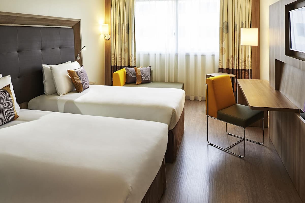 A hotel room with two beds, a desk, and a chair.
