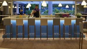A modern bar area with a central island, bar stools, and pendant lighting. - Novotel Rio de Janeiro Parque Olímpico (Rio de Janeiro)