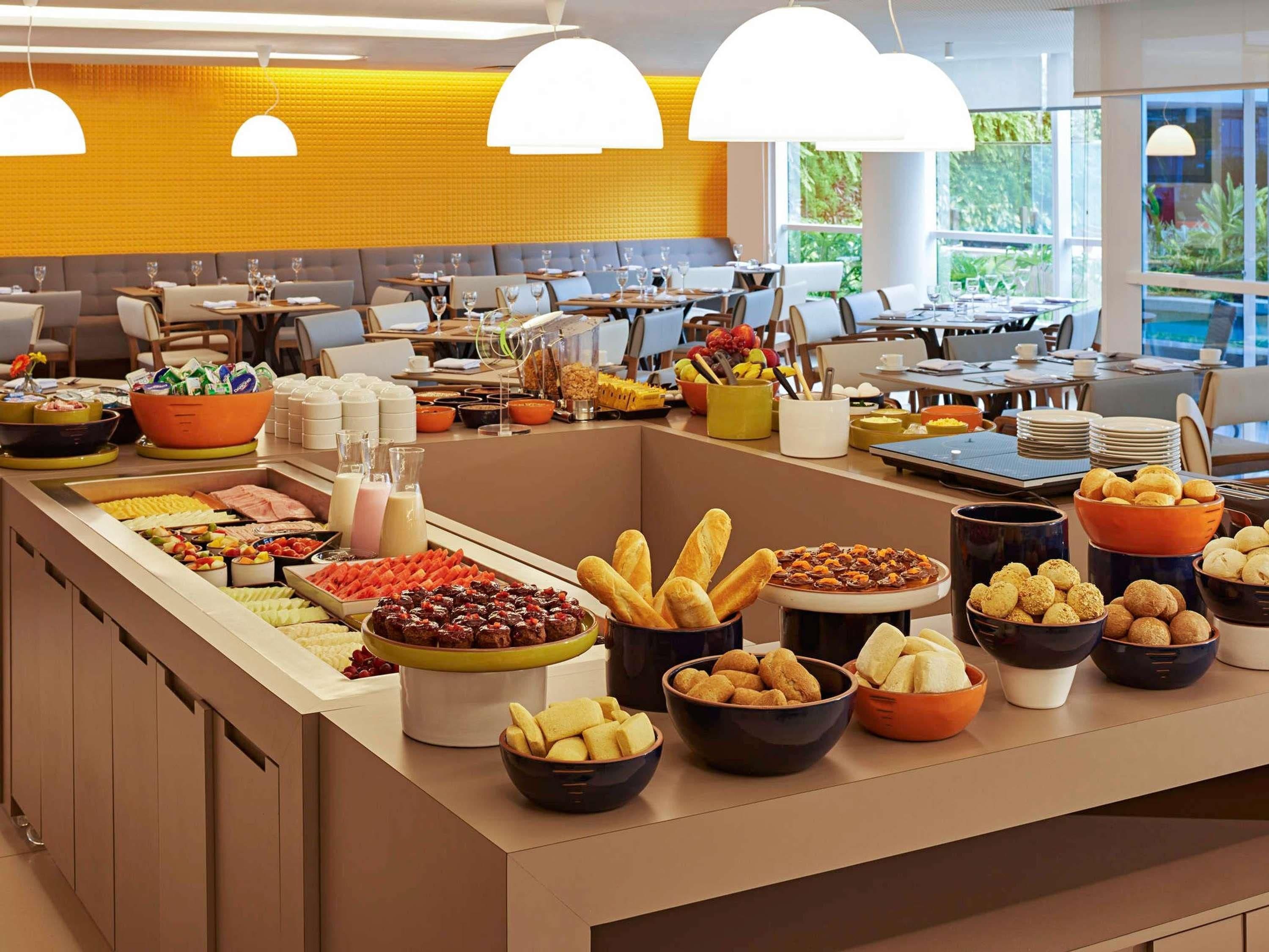 A buffet setup with various food items and beverages, a seating area with tables and chairs, and a bright interior with natural light.