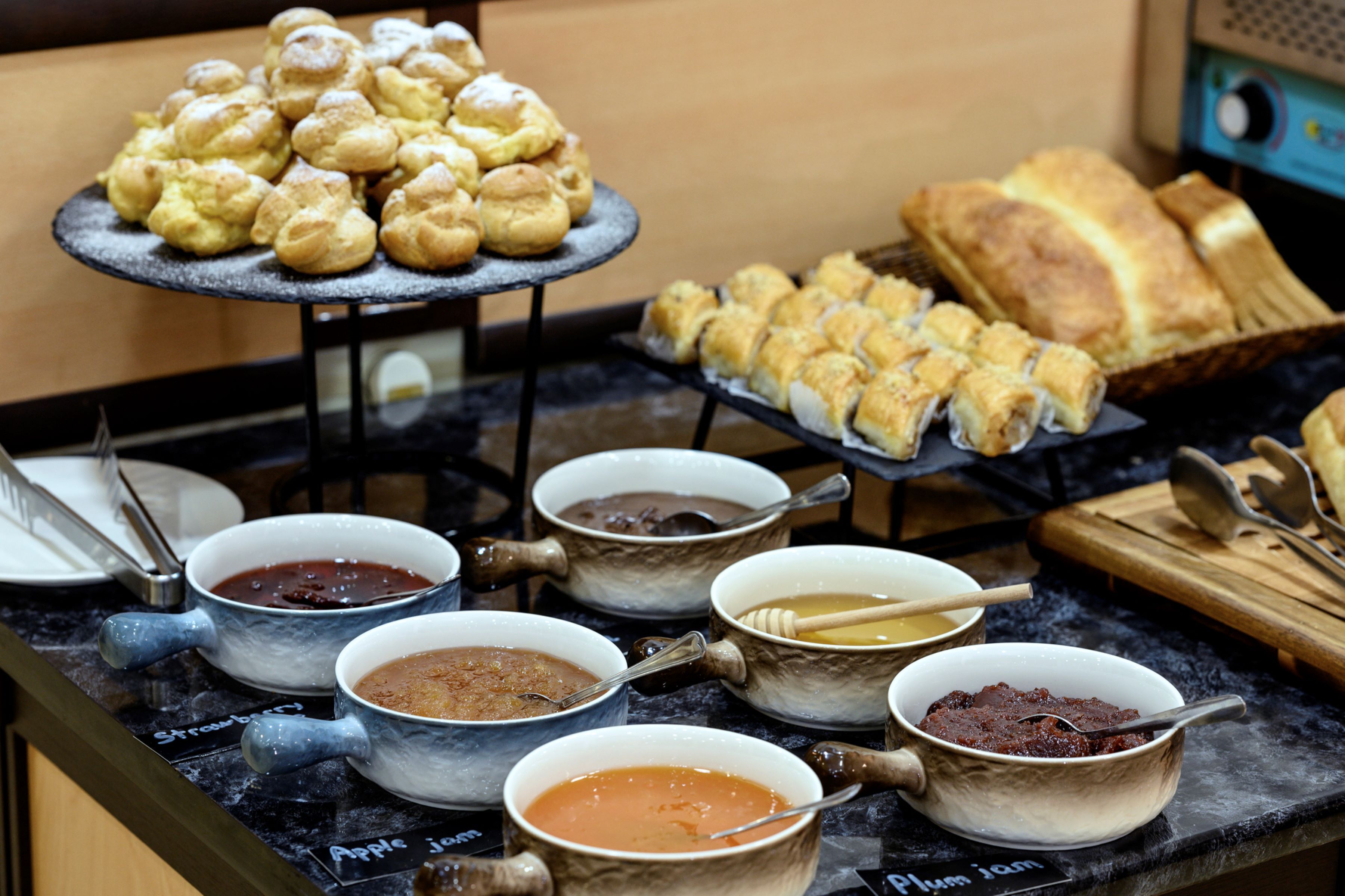 A buffet with various food items including pastries, bread, and bowls of different sauces.