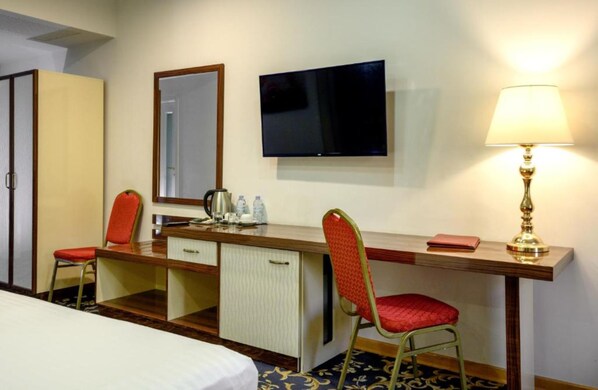 A hotel room with a bed, a desk with a chair, a television, a lamp, and a wardrobe. - Royal Plaza by Stellar Hotels, Yerevan (Yerevan)
