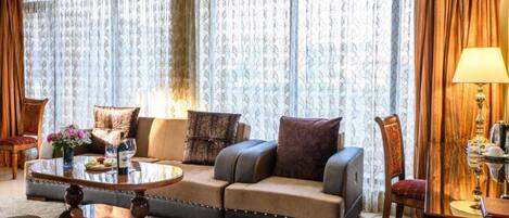 A living room with a sofa, a round coffee table, and a chair. There is a lamp on a side table.