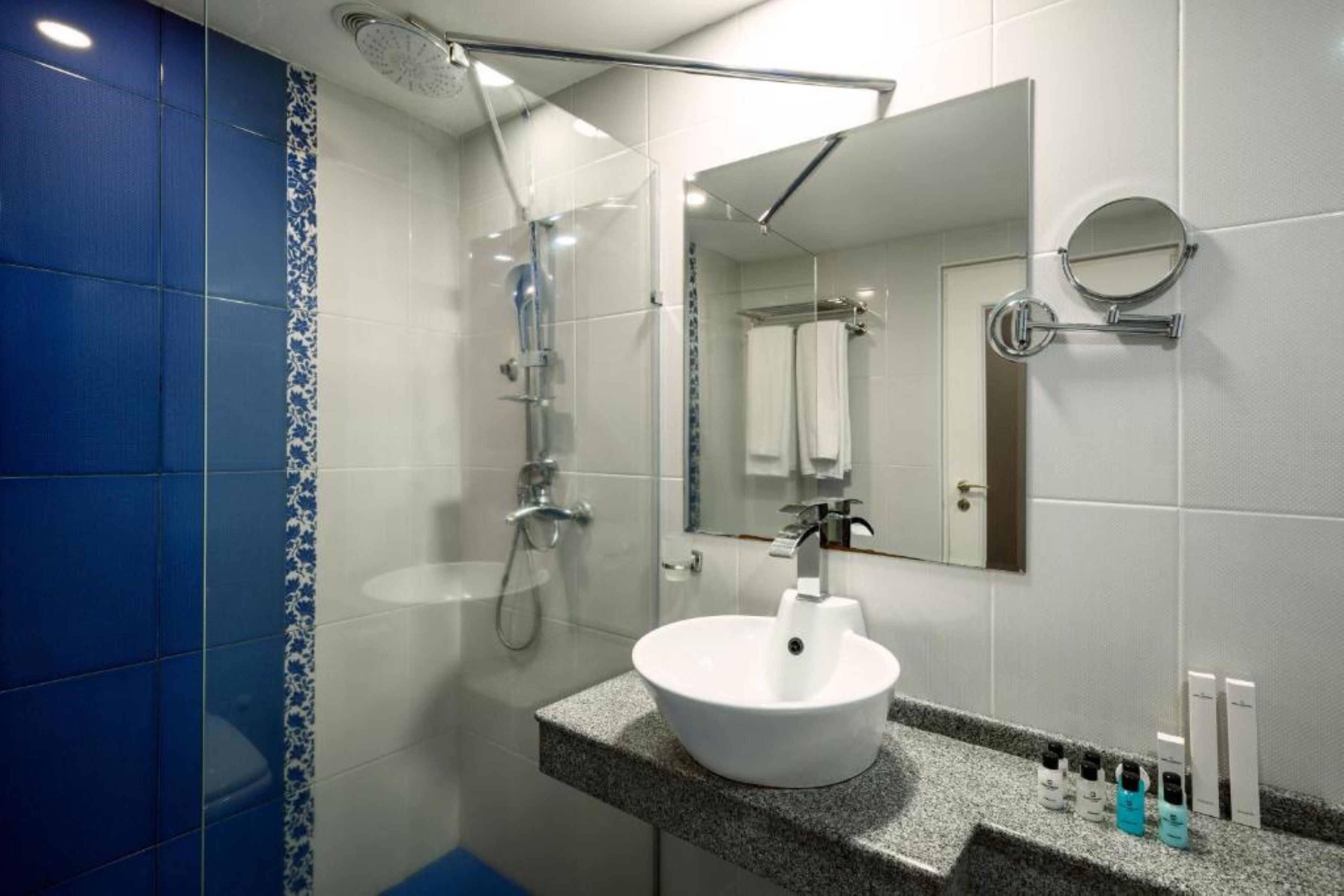 Un baño moderno con un lavamanos blanco, un espejo grande y una ducha.
