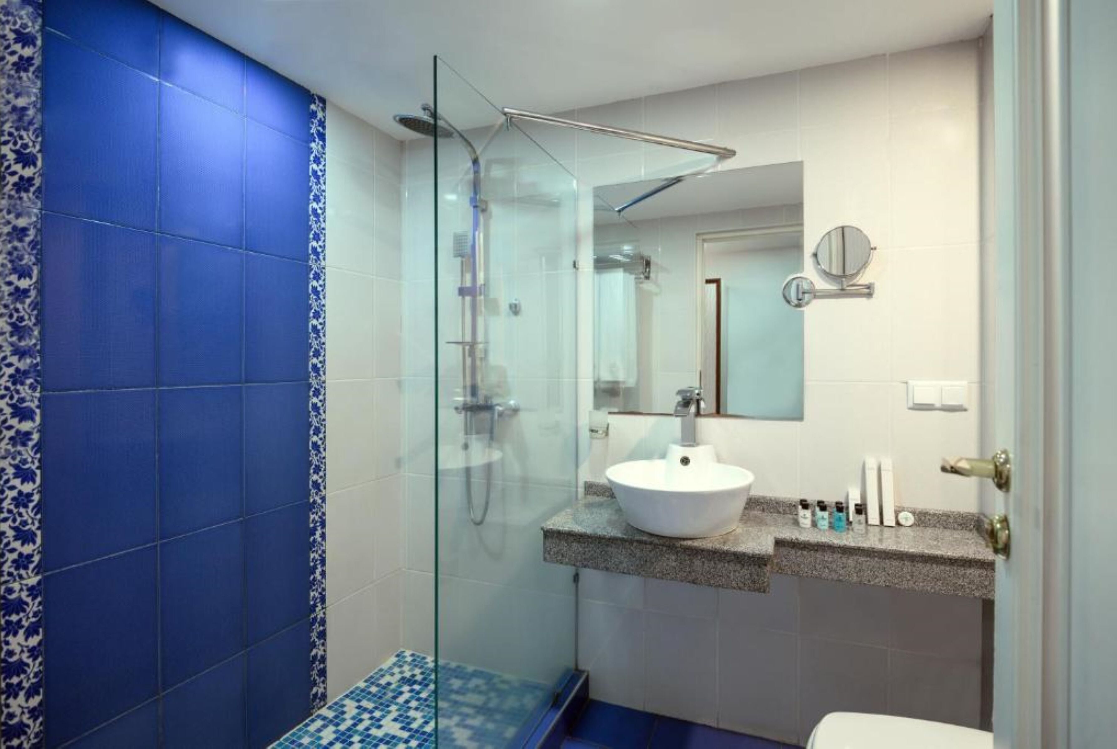 A bathroom with a glass-enclosed shower, a white sink, and a mirror above it.