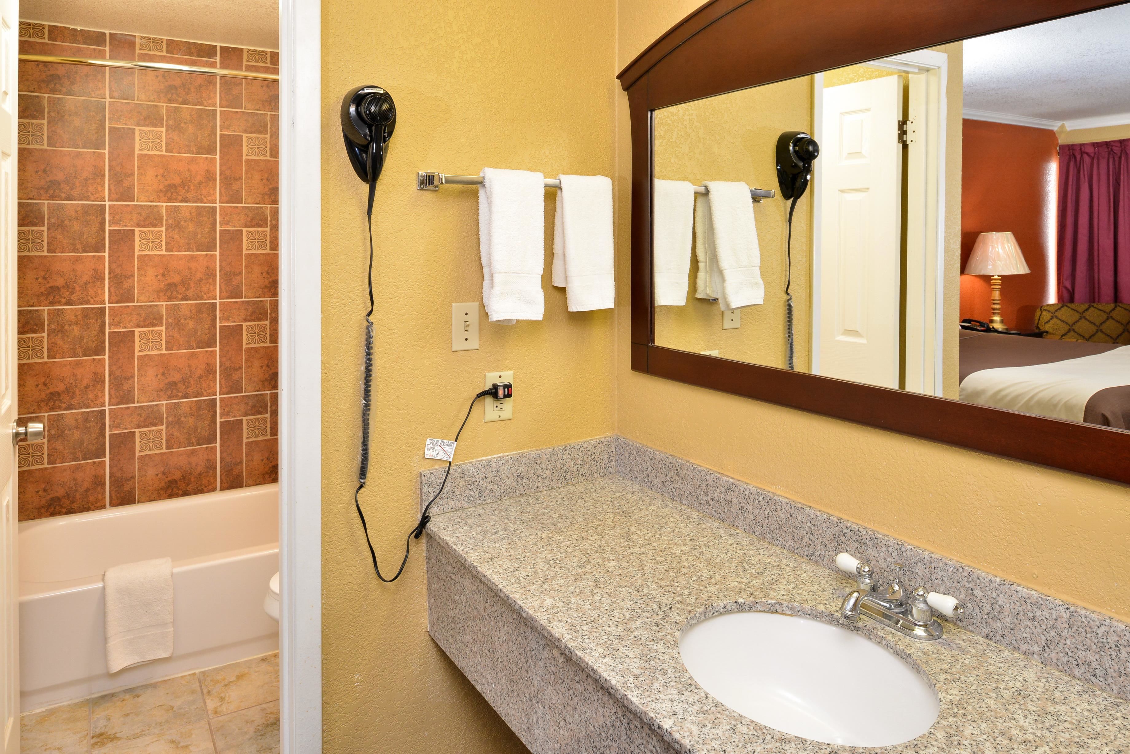 Une salle de bain avec un lavabo en granit, un miroir et un sèche-cheveux fixé au mur.