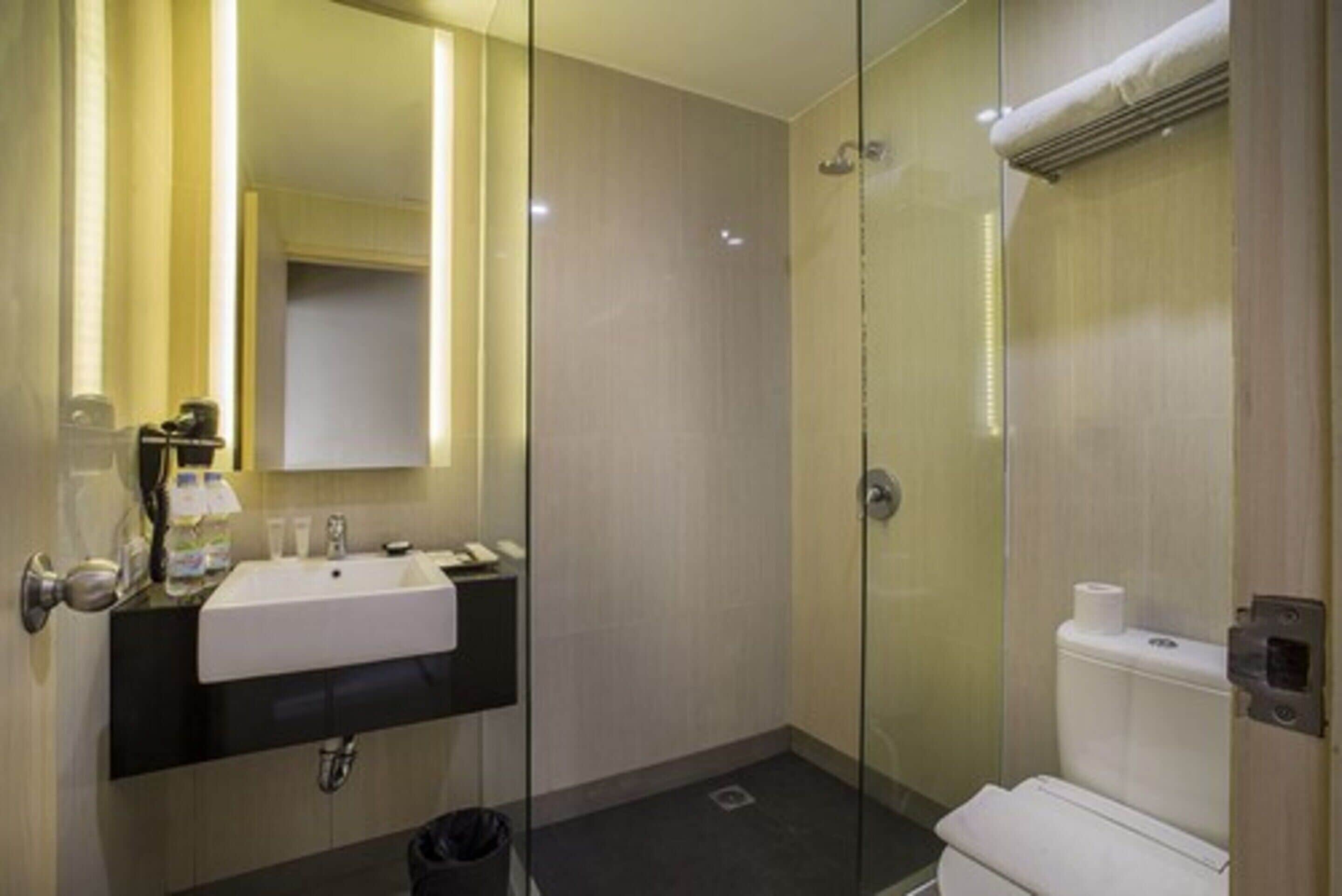 Une salle de bain moderne avec une douche à parois de verre, un lavabo blanc et des toilettes.