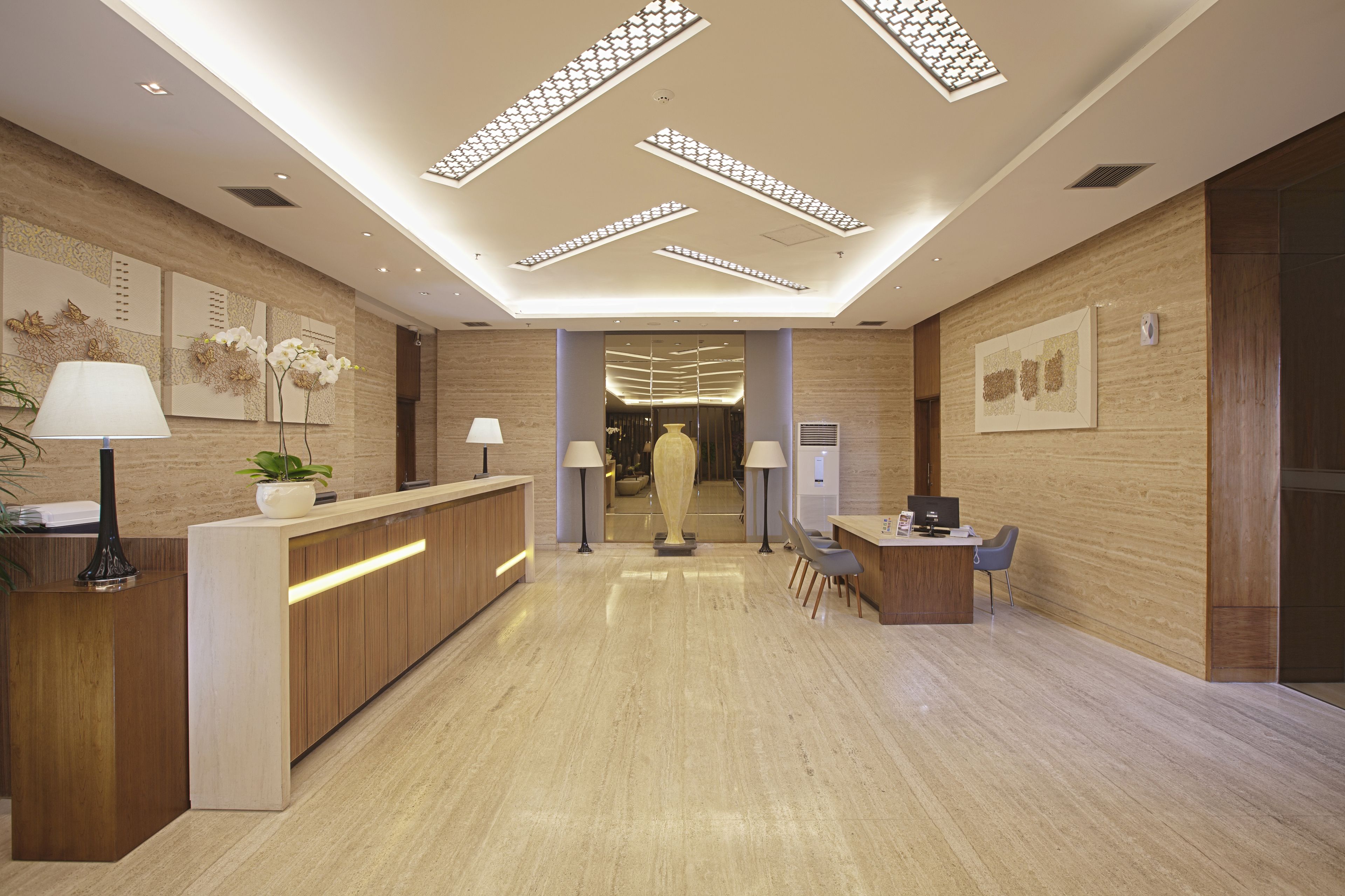 Un hall d’hôtel moderne comprenant un comptoir d’accueil, un espace salon et une vue sur la salle à manger.