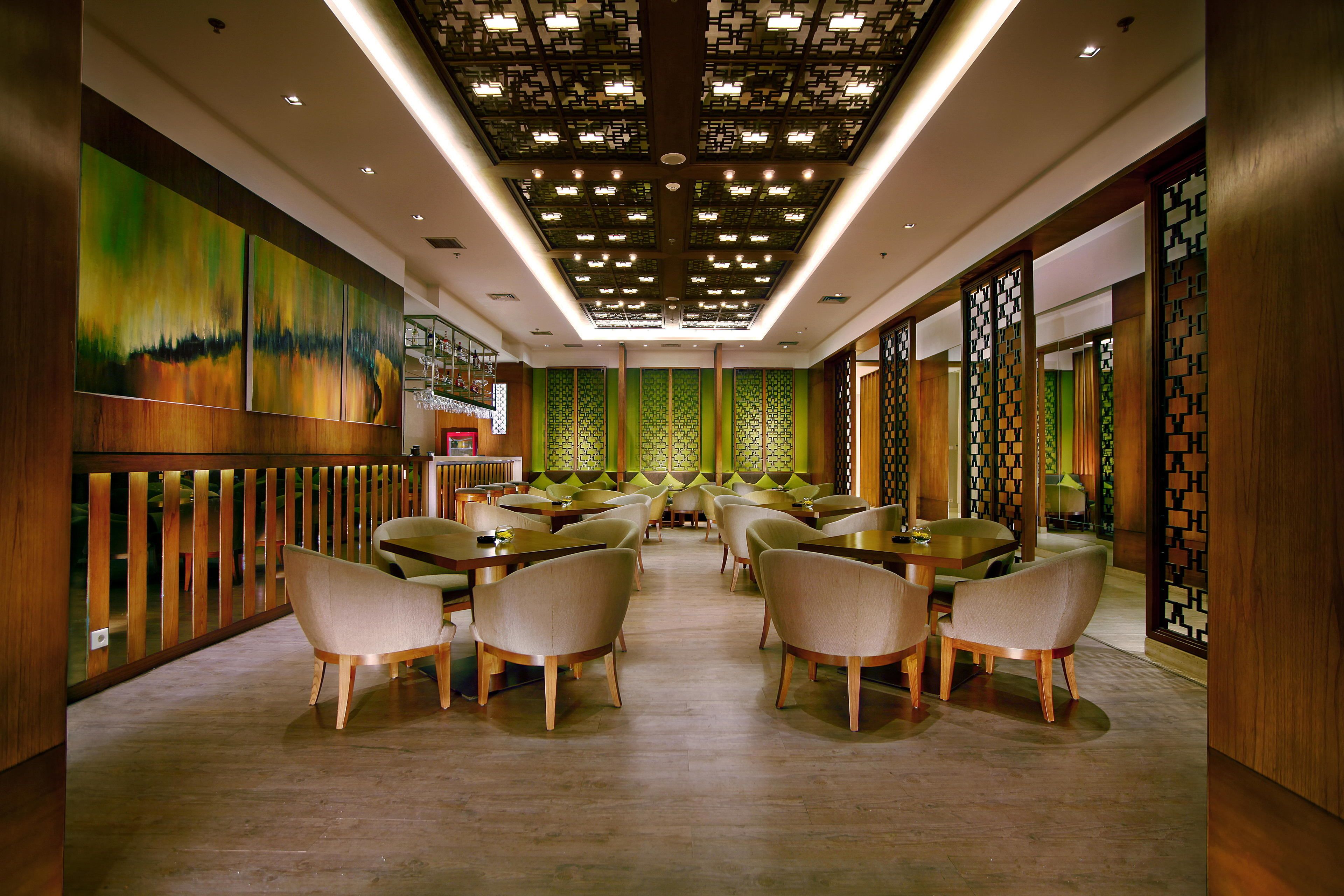 Un restaurant spacieux avec de hauts plafonds, des boiseries et des murs décoratifs de couleur verte.