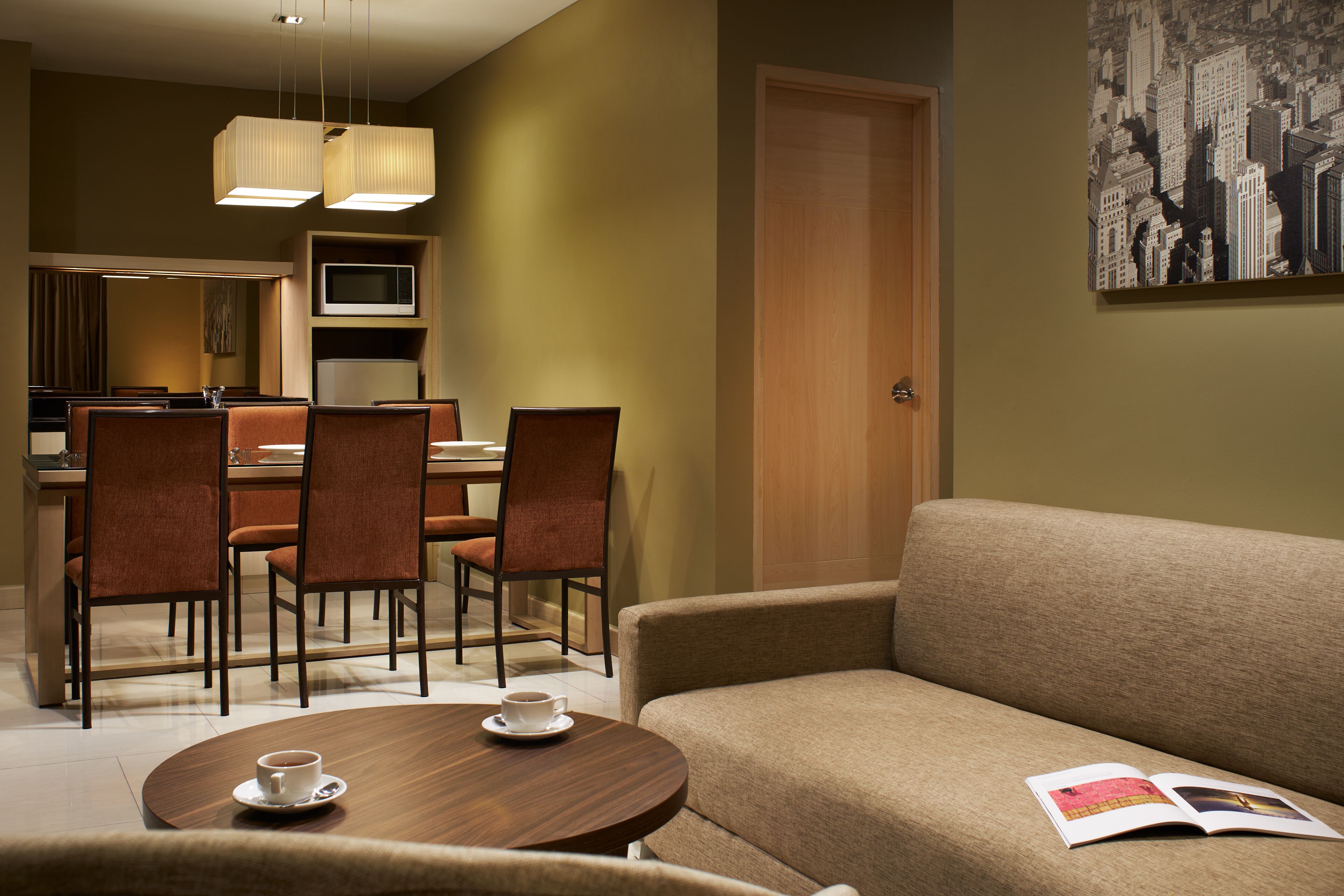 A hotel room with a dining area, a sofa, a coffee table, and a television.