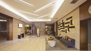 A modern lobby with a reception desk, seating area, and decorative wall panels.