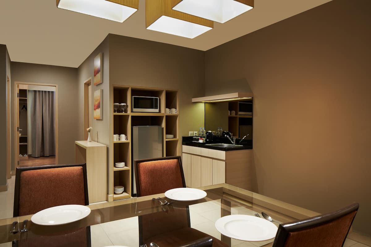 Ein modernes Hotelzimmer mit Essbereich, einer Küchenzeile und einem Badezimmer.