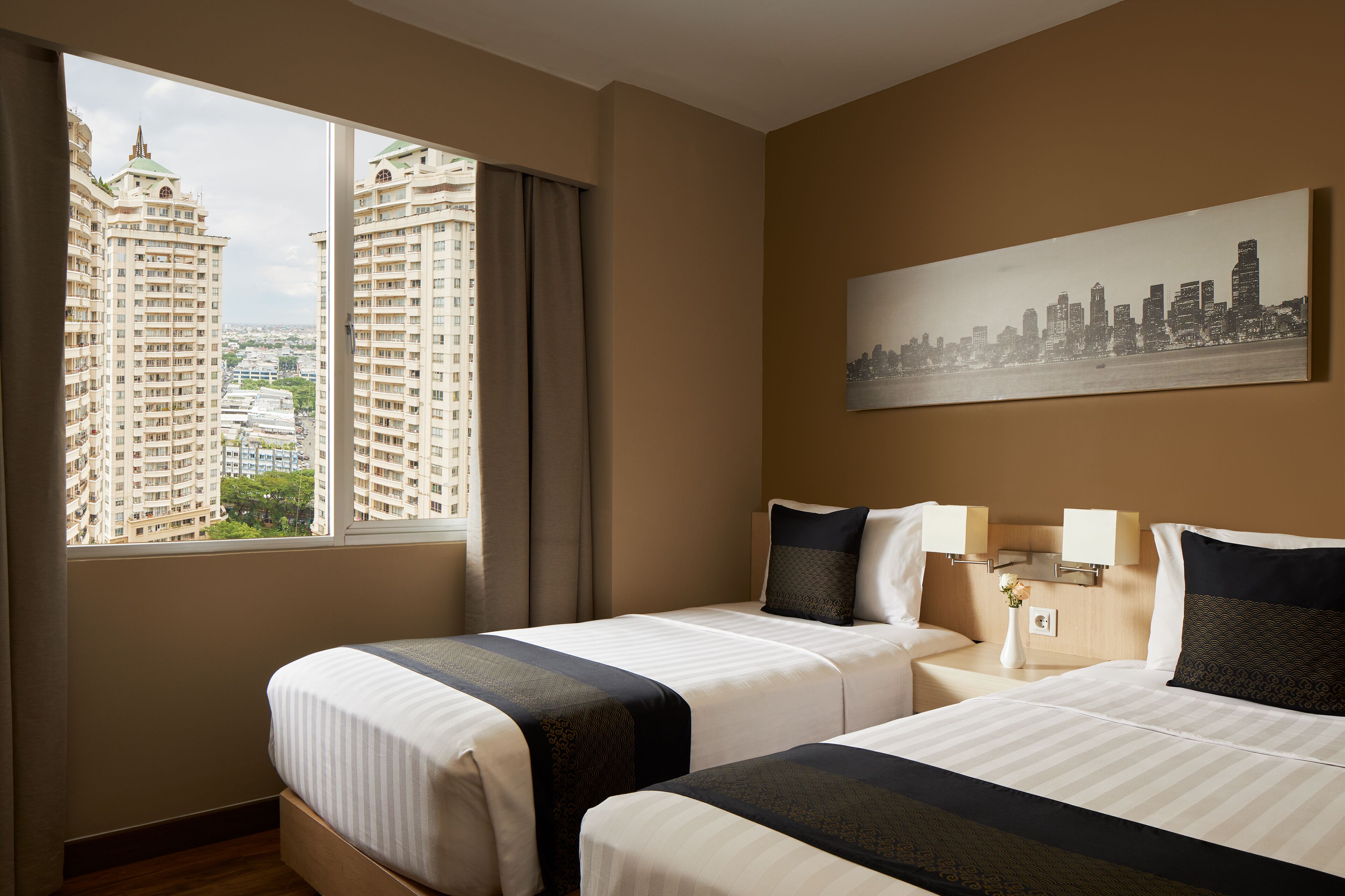 Habitación de hotel con dos camas, vista a la ciudad y un cuadro enmarcado en la pared.