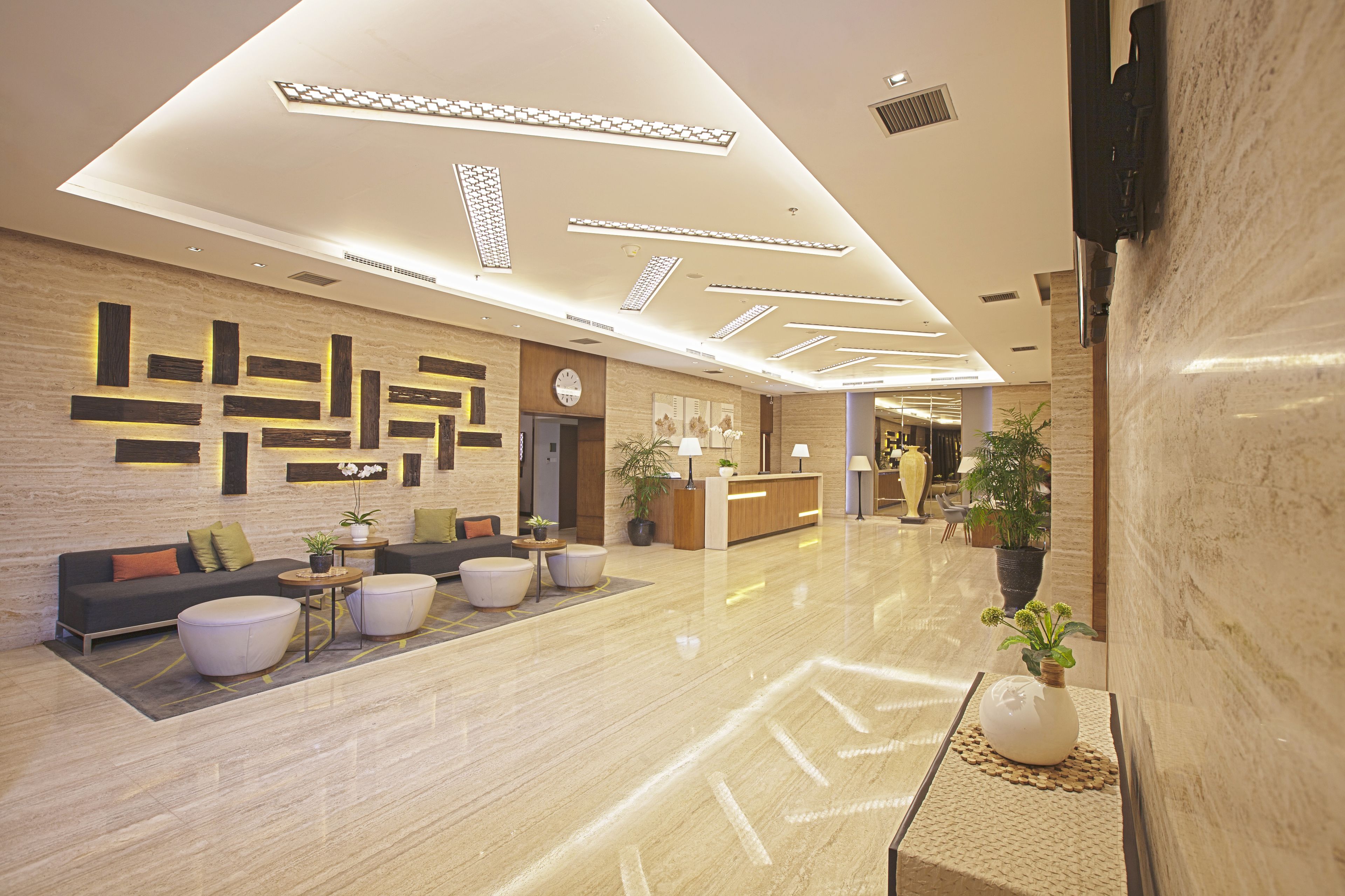 A modern lobby with a reception desk, seating area, and decorative wall panels.