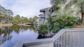 A waterfront property with a dock, a small bridge, and a row of houses with balconies. - Ocean Cove At Palmetto Dunes (Hilton Head Island)