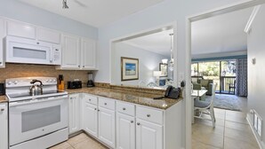 A modern kitchen with white cabinetry, a granite countertop, and a built-in oven. - Ocean Cove At Palmetto Dunes (Hilton Head Island)