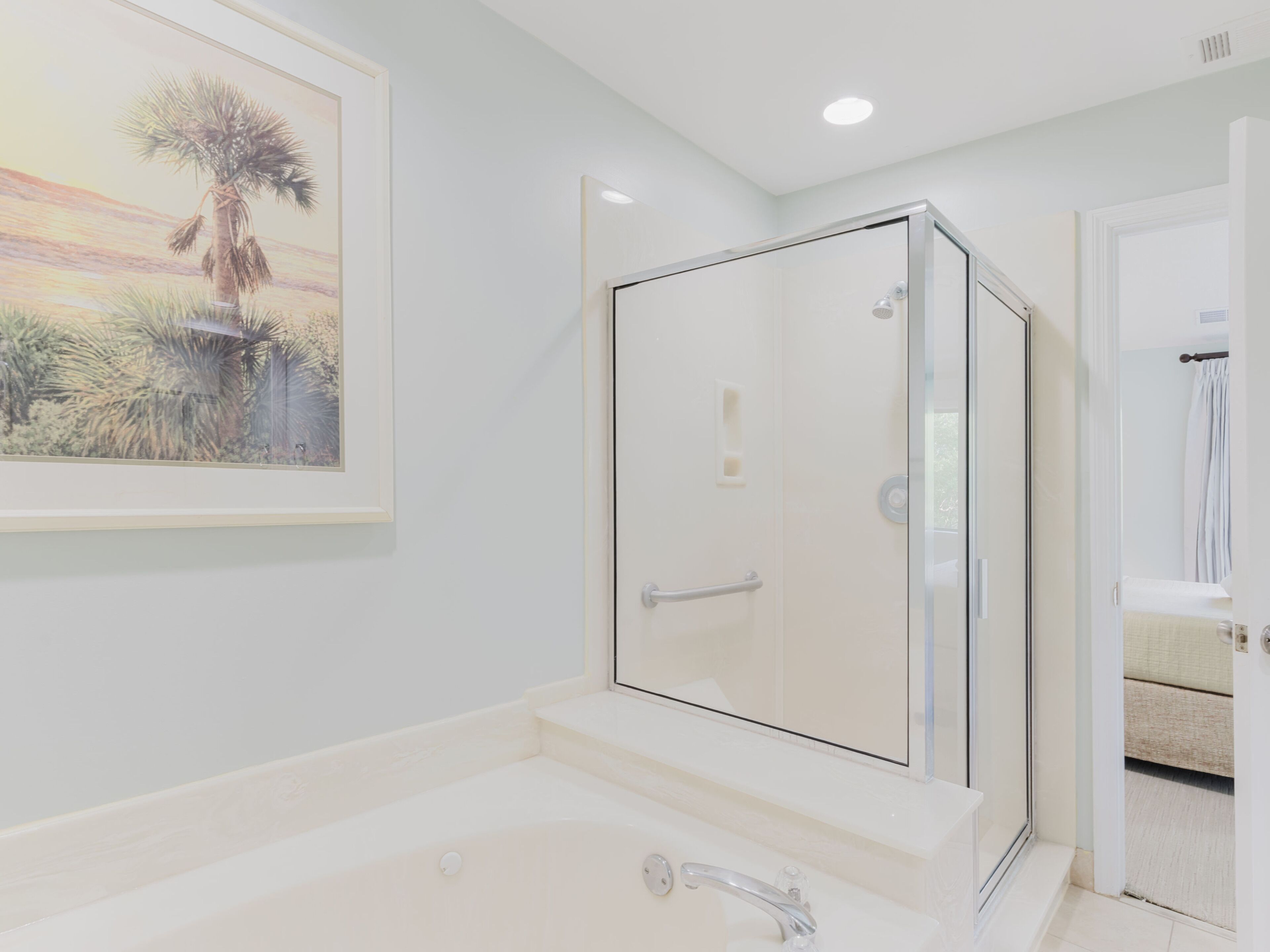 A modern bathroom with a glass-enclosed shower, a bathtub, and a framed landscape painting on the wall.