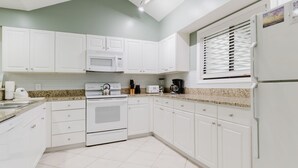 Cocina con armarios blancos, microondas, estufa y refrigerador.