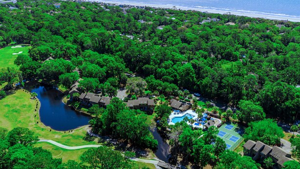 An aerial view of a resort with a swimming pool, tennis court, and a golf course. - Spinnaker At Shipyard (Hilton Head Island)