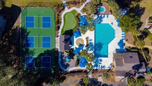 An aerial view of a resort with a tennis court, a pool area with sun loungers, and a small garden. - Spinnaker At Shipyard (Hilton Head Island)