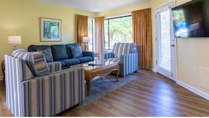 A living room with a sofa, two armchairs, a coffee table, and a flat-screen TV. - Spinnaker At Shipyard (Hilton Head Island)