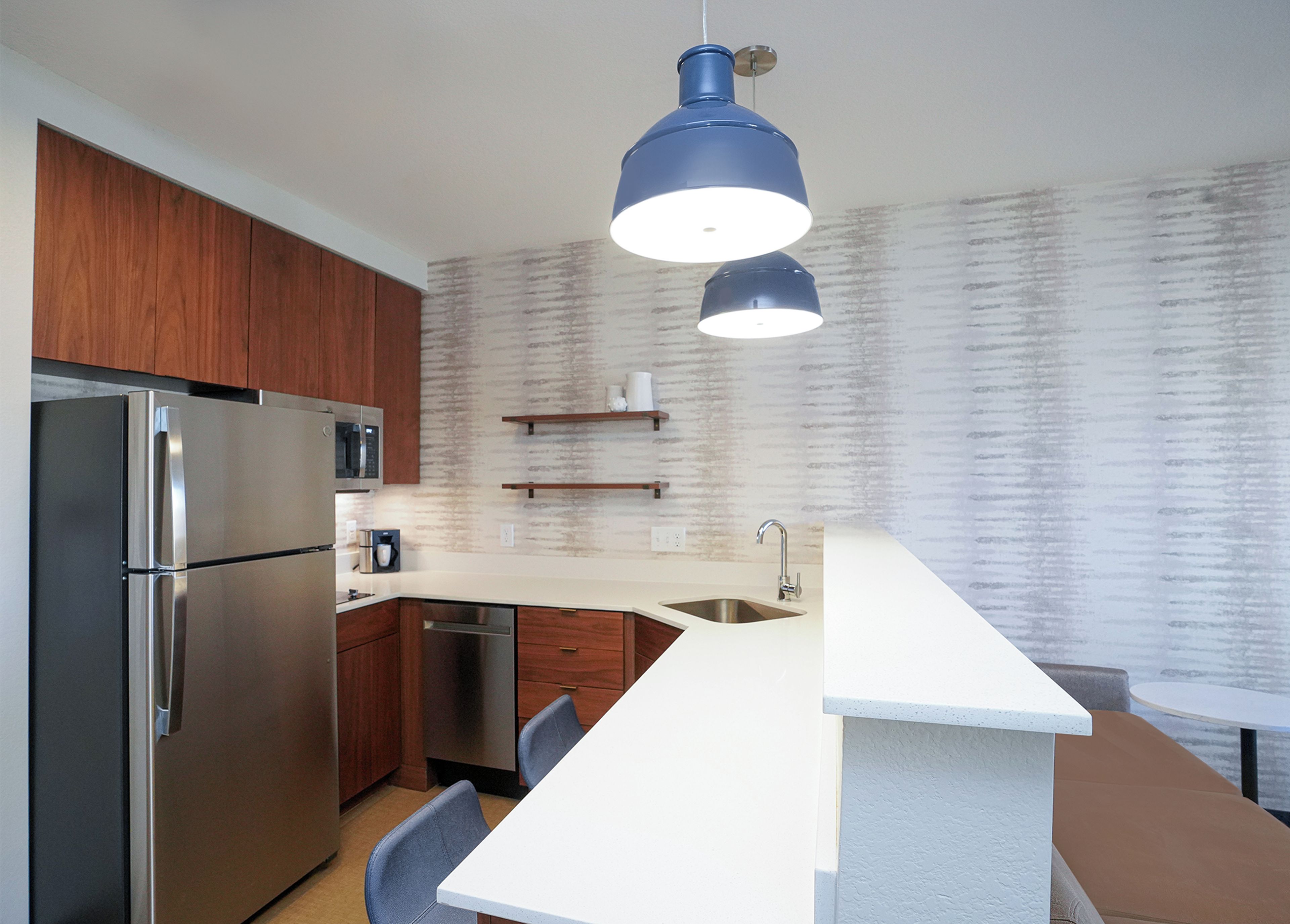 A modern kitchen with a stainless steel refrigerator, a microwave, a sink, and a bar area.