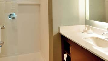 Une salle de bain moderne avec une douche à parois de verre, un lavabo blanc et un grand miroir.