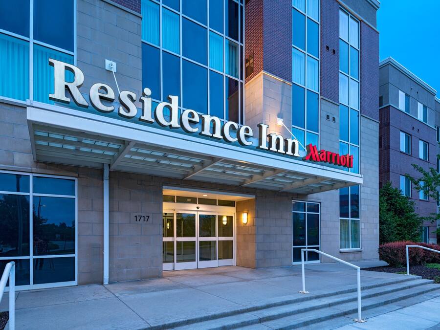 A modern building with a large entrance, a sign reading "Residence Inn Marriott," and a number "1717" on the wall.