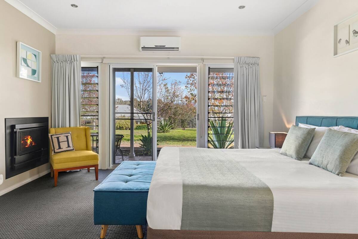 Ein Hotelzimmer mit Bett, Sessel, Kamin und Blick ins Freie.