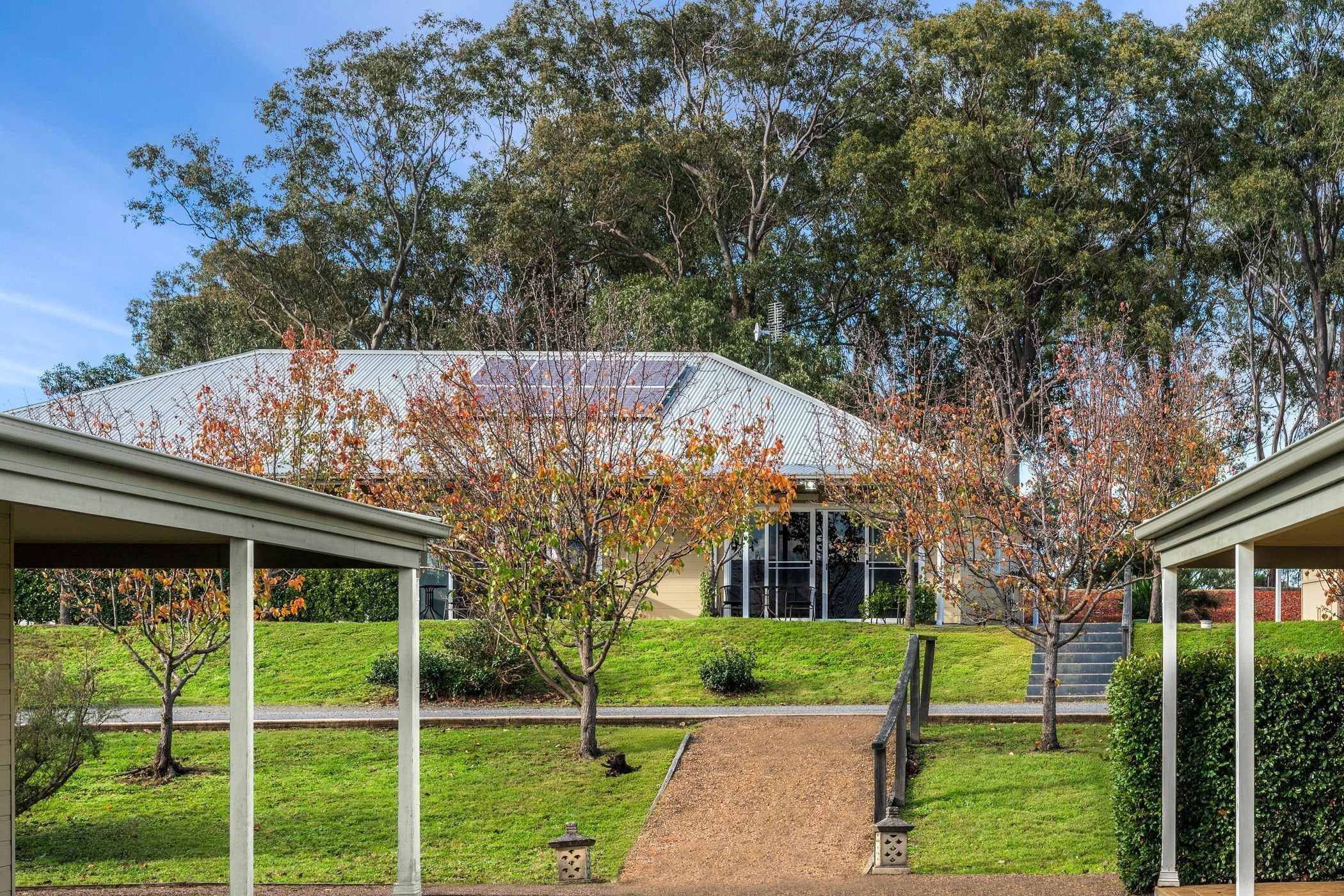 A building with a modern design, featuring a covered walkway and a grassy area with trees.
