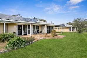 A building with a flat roof, solar panels, and a well-maintained lawn.