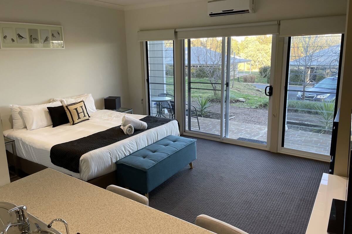 Ein Hotelzimmer mit Bett, Schreibtisch, Stuhl, Fenster und Deckenventilator.