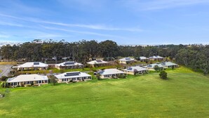 A residential area with multiple houses featuring solar panels on the roofs, surrounded by green fields and trees. - H Boutique Hotel (Pokolbin)