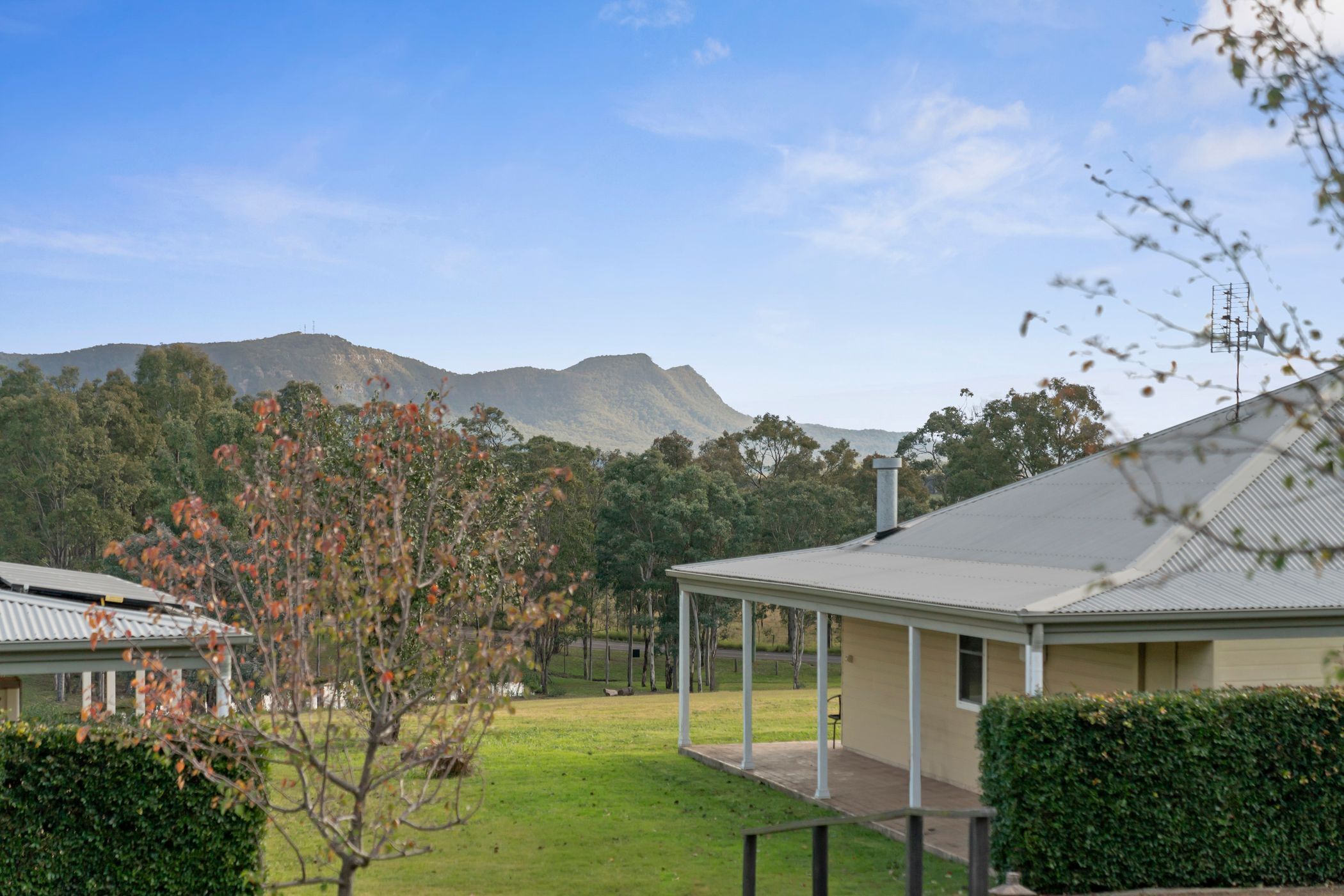 A residential area with a house featuring a covered porch and a view of a mountain in the background.