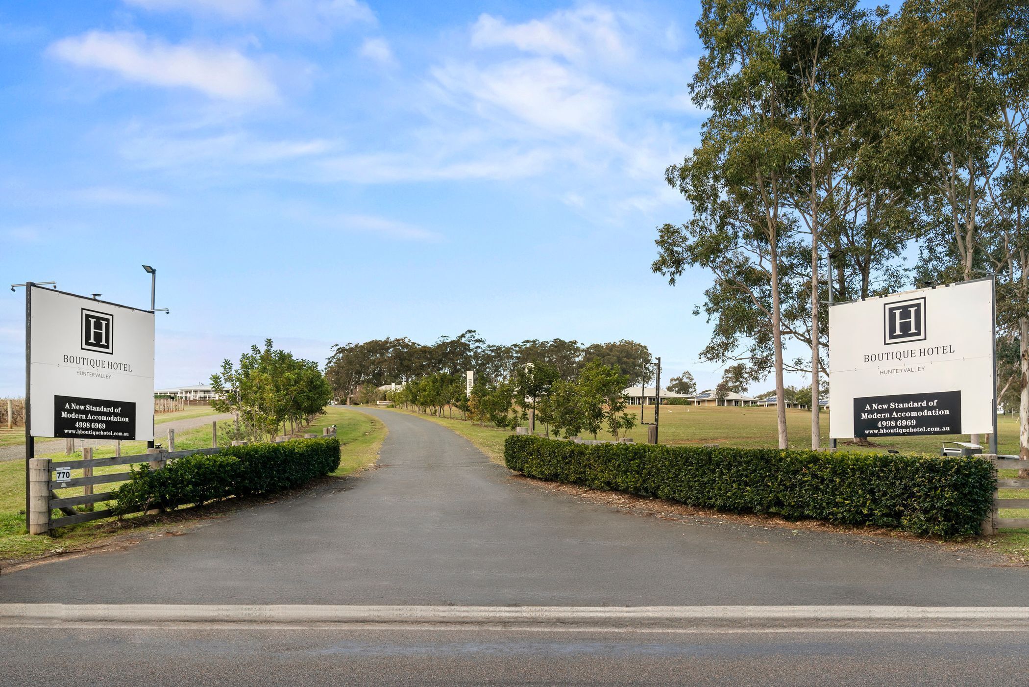 A road leading to a hotel entrance with signage for Boutique Hotel Hunter Valley.