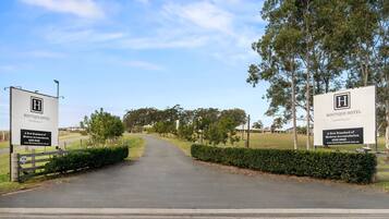 A road leading to a hotel entrance with signage for Boutique Hotel Hunter Valley.