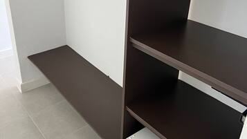 A room with a built-in wardrobe featuring multiple shelves and a hanging rod.