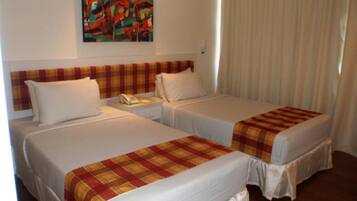 Una habitación de hotel con dos camas, un cuadro en la pared y una ventana con cortinas.