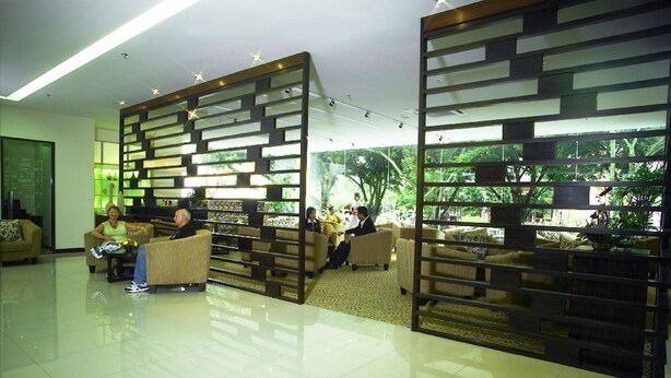 A spacious lobby with modern furniture and a large window offering a view of greenery. - The Jerai Hotel Alor Star (Alor Setar)