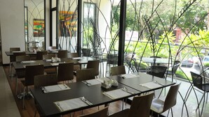 A restaurant with multiple tables and chairs, large windows with a view of greenery and parked cars. - The Jerai Hotel Alor Star (Alor Setar)