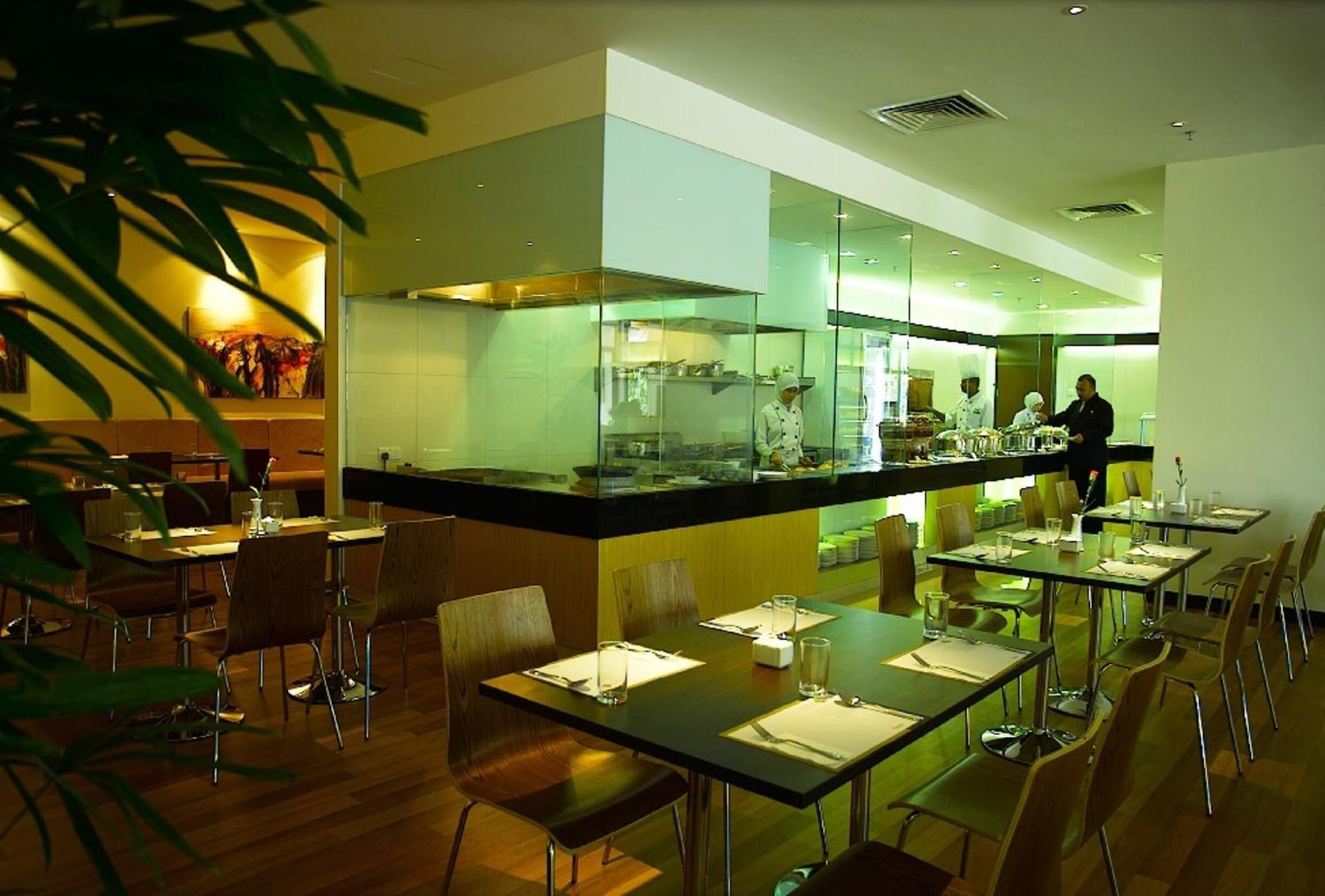A modern restaurant with a central bar area, multiple dining tables, and chairs.