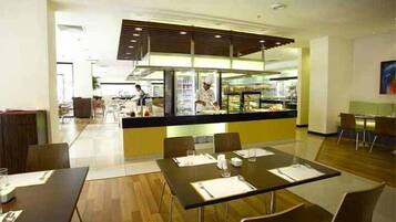 A modern restaurant with a central counter, dining tables, and chairs.