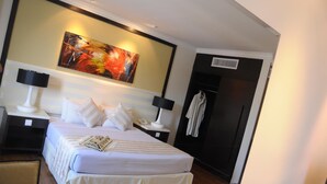A hotel room with a bed, two bedside tables, a painting above the bed, a coat rack, and a door. - The Jerai Hotel Alor Star (Alor Setar)
