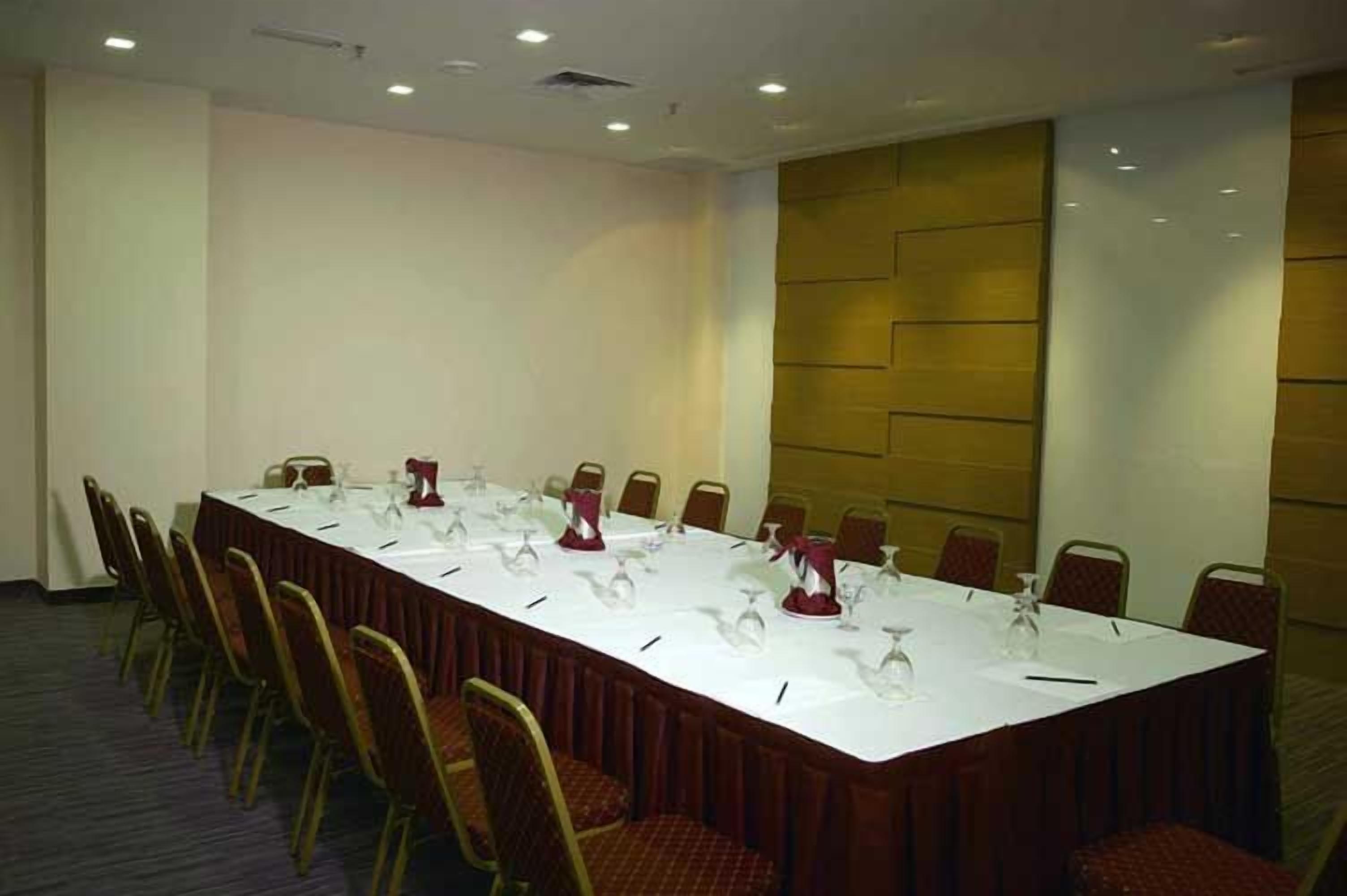 Une salle de conférence avec une longue table, des chaises et un tableau blanc.