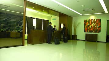 A reception area with a reception desk, a waiting area with a sofa, and a large abstract painting on the wall.