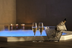 A hot tub with two champagne flutes and a bucket of ice.