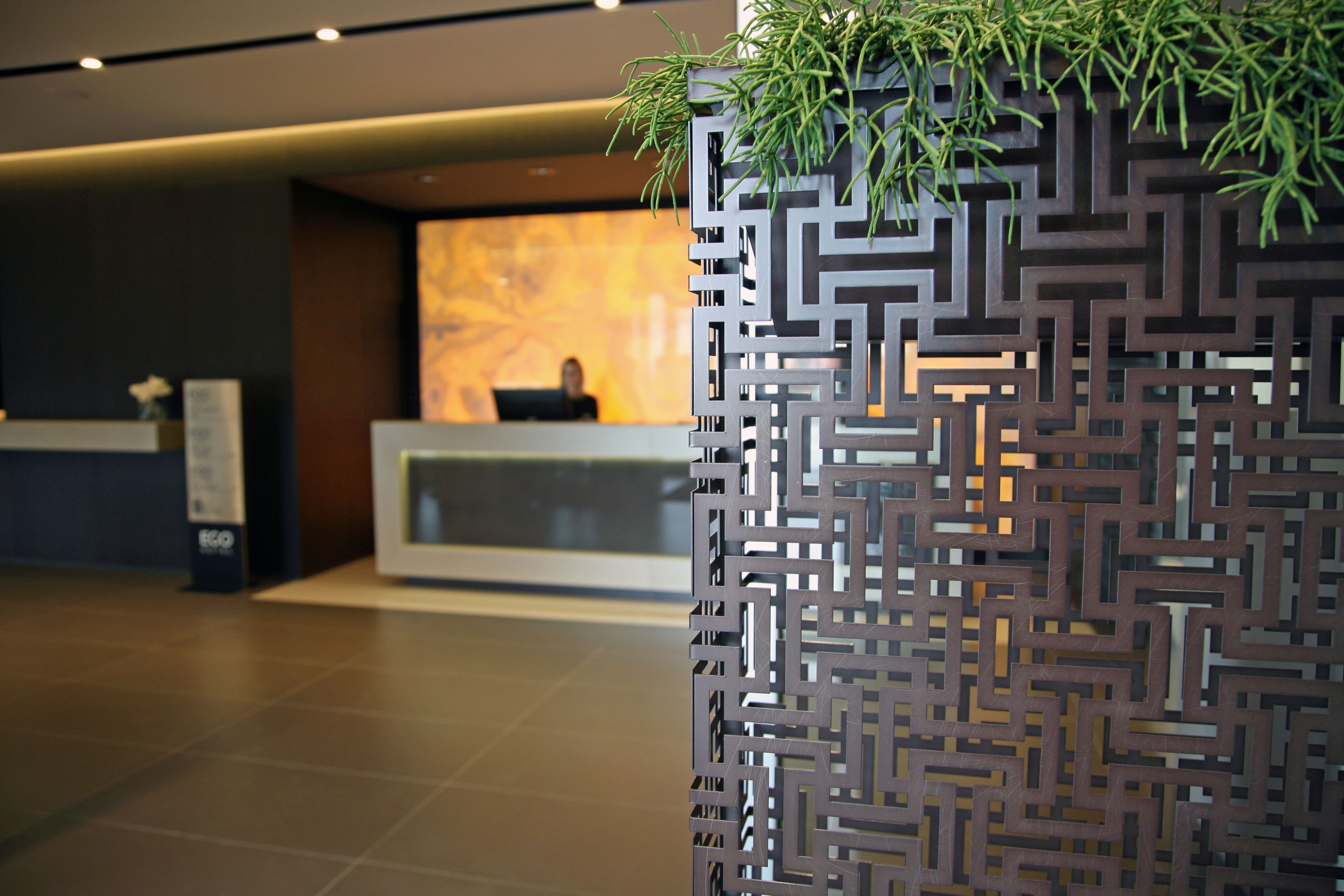 Een receptiegedeelte met een modern ontwerp, met een geometrisch patroon aan de muur en een receptiebalie.
