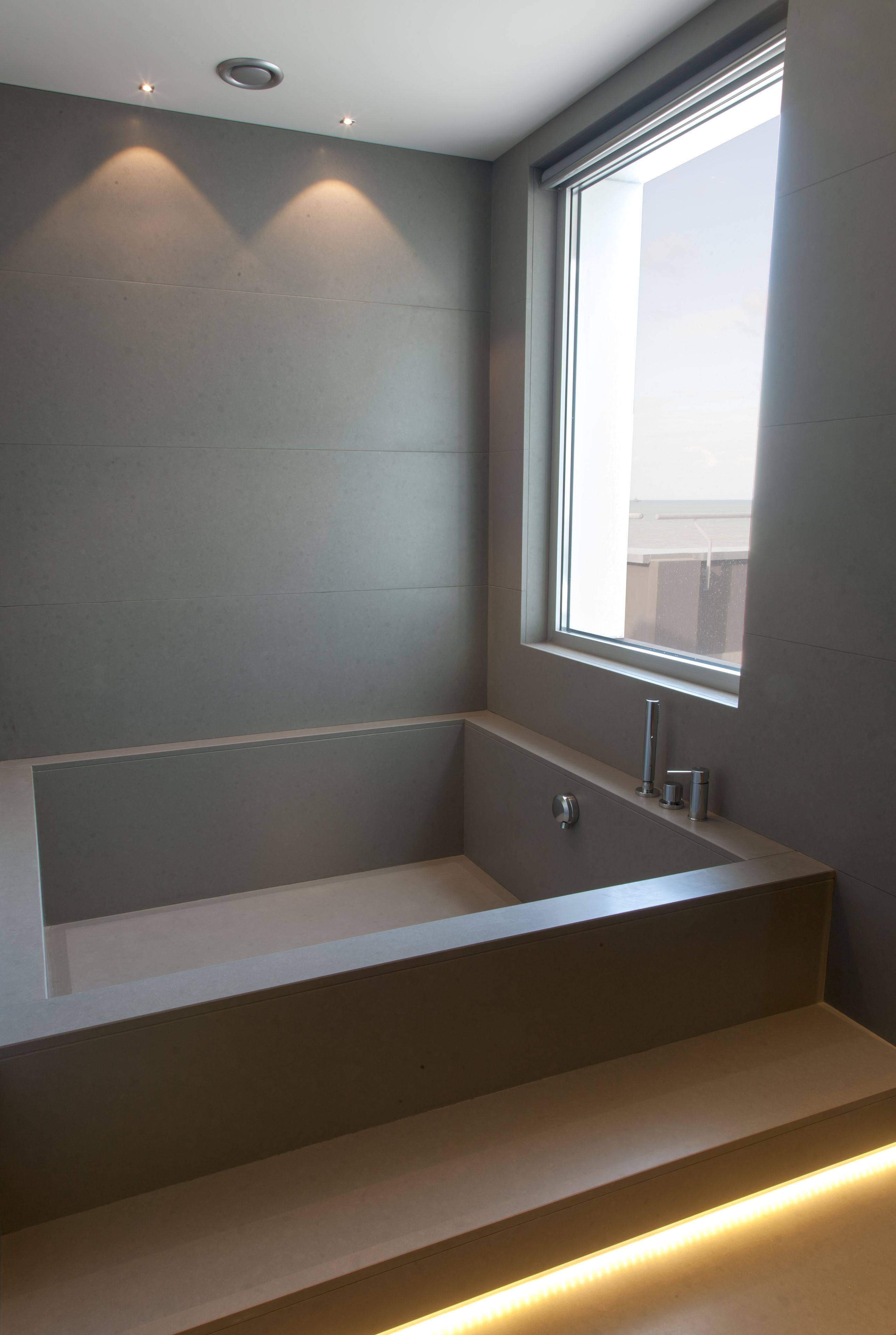 Une salle de bain moderne avec une baignoire intégrée, une fenêtre et un éclairage encastré.