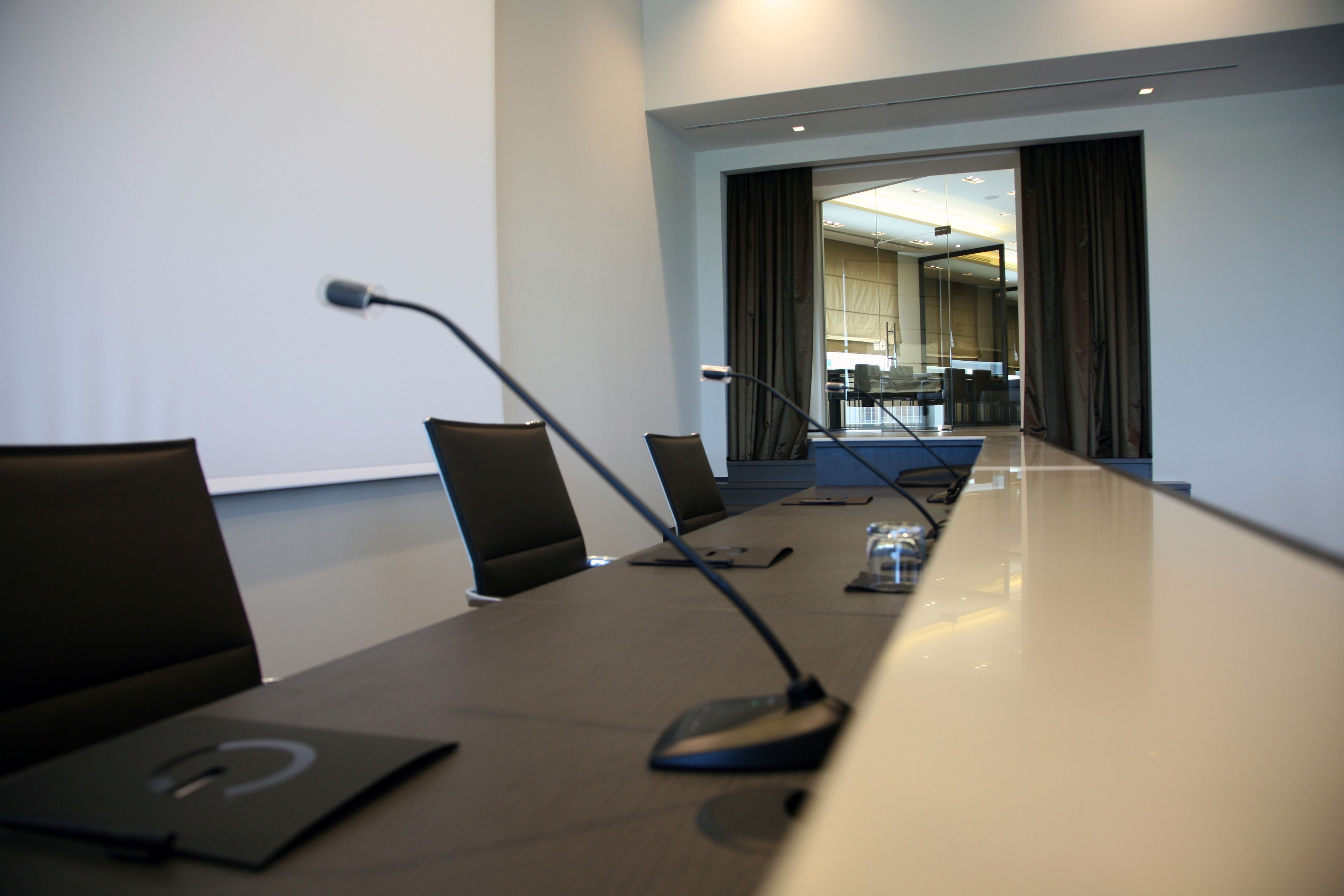 Un salón de conferencias con una larga mesa, sillas y una pantalla para proyector.