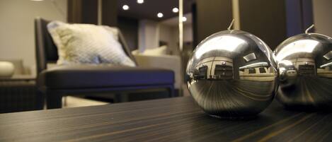A modern hotel room with a large bed, a bedside table with two spherical objects, and a well-lit room with a lamp.